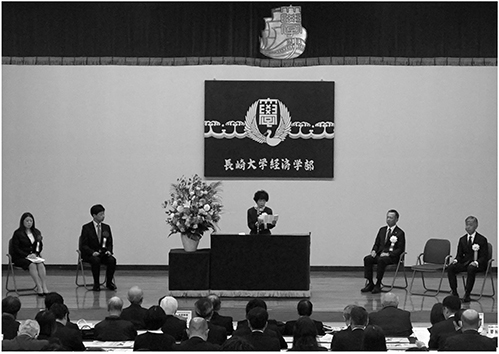 記念式典の様子（式辞を述べる井田学部長）。